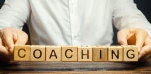 Wooden blocks with the word Coaching in the hands of a man.