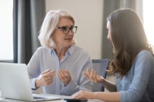 Different age employees sitting at desk talking