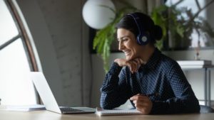 Smiling female employee taking part in virtual learning and development session on laptop