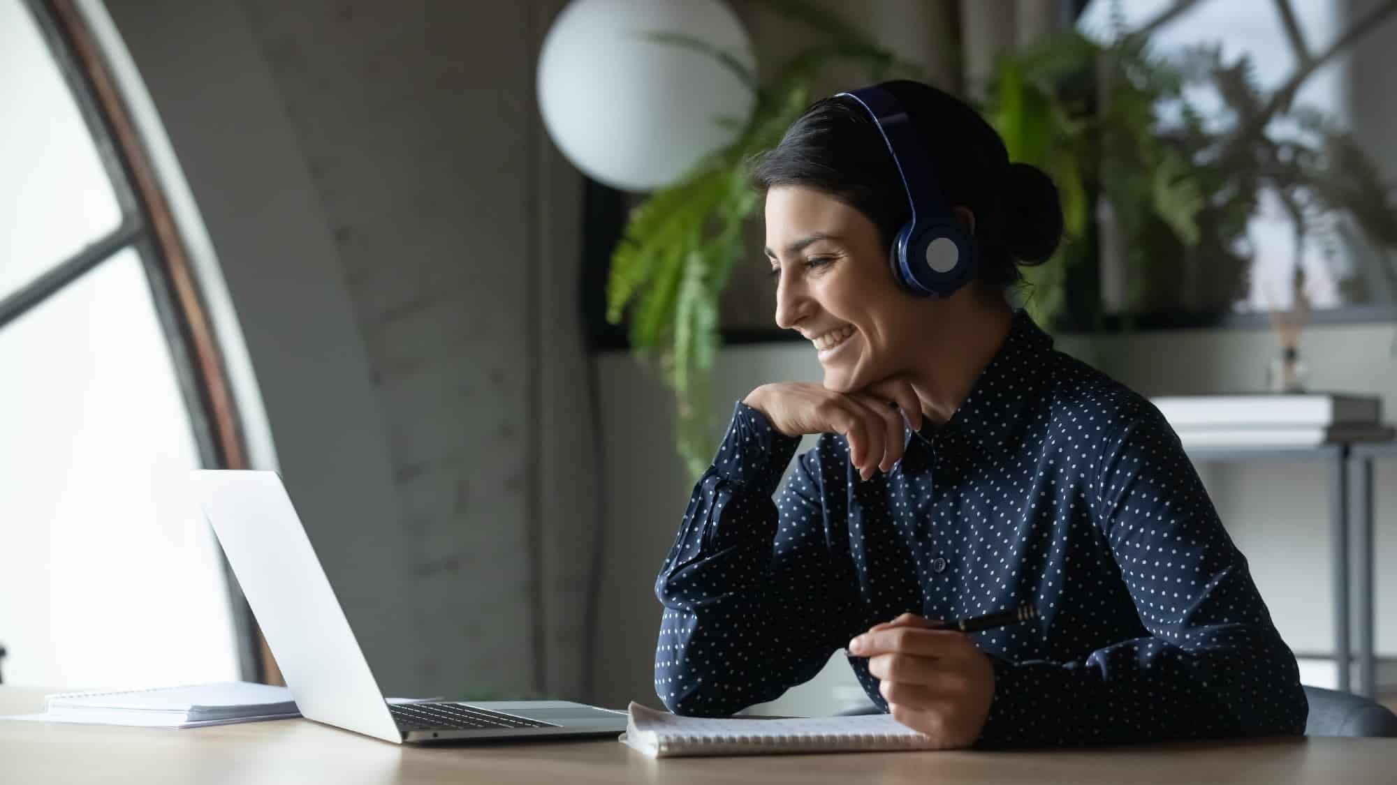 Smiling female employee taking part in virtual learning and development session on laptop