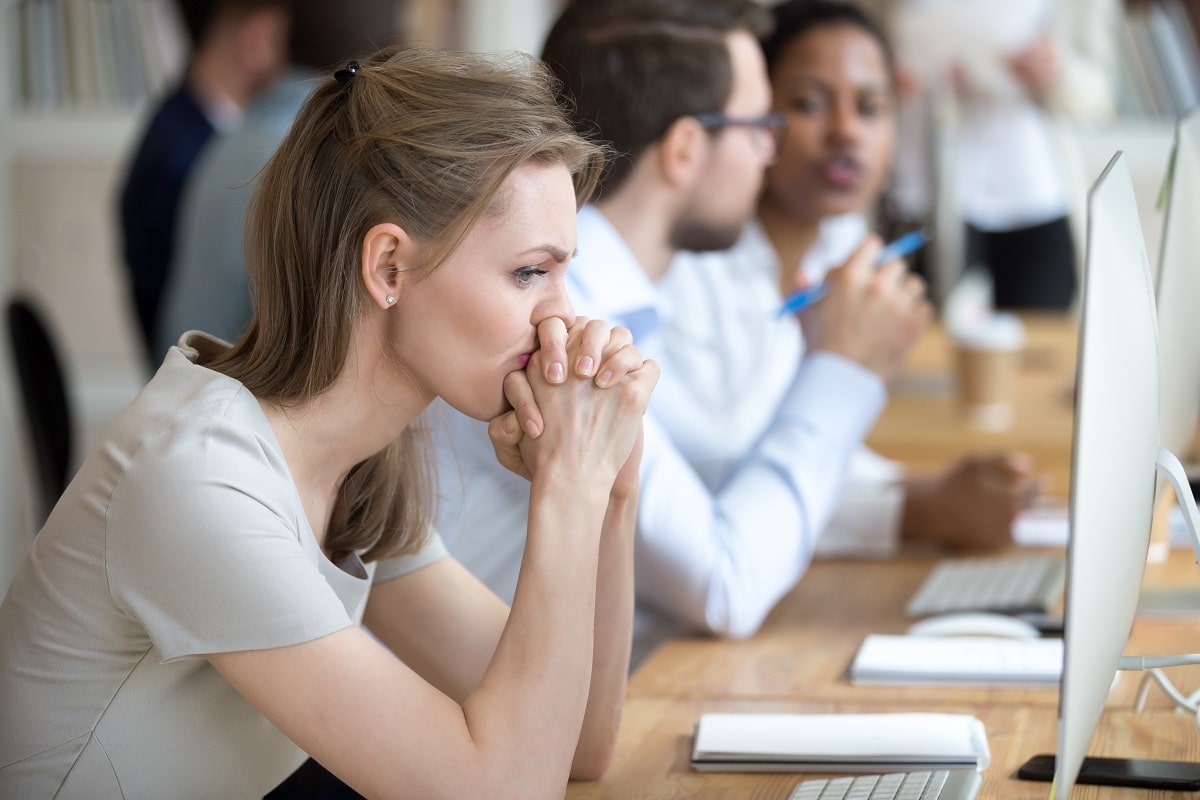 Woman employee sitting at desk having problem or doubt about business moment