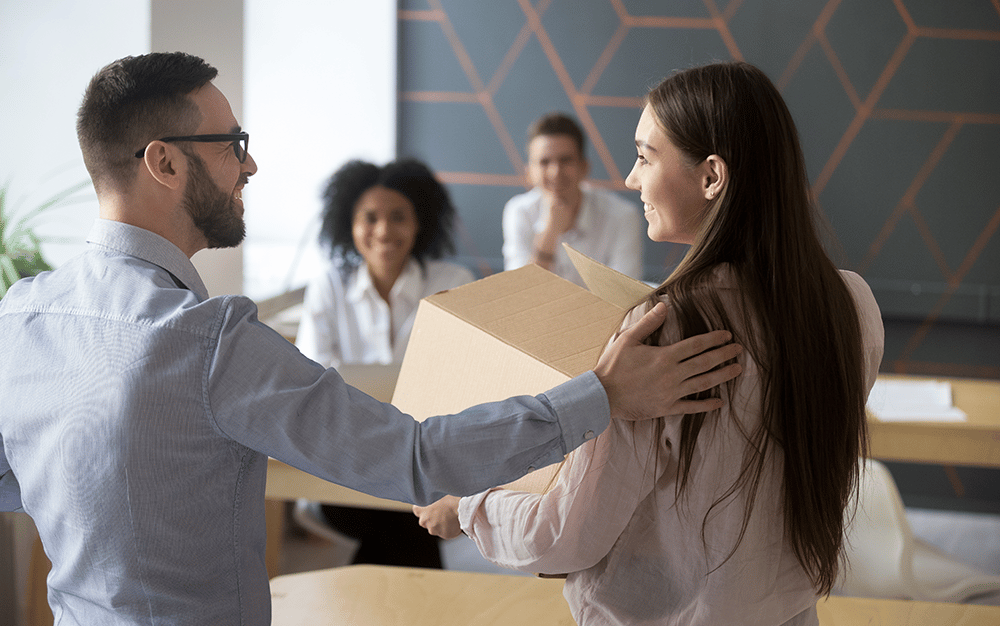 man patting woman on the back while she is holding a box