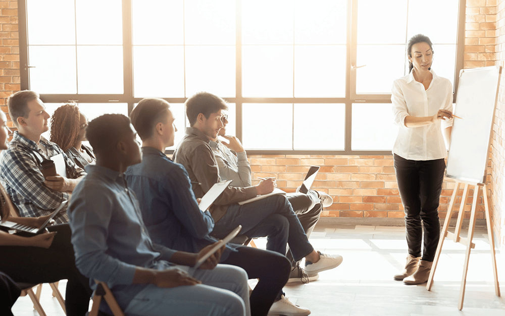 woman demonstrating something to room of new hires