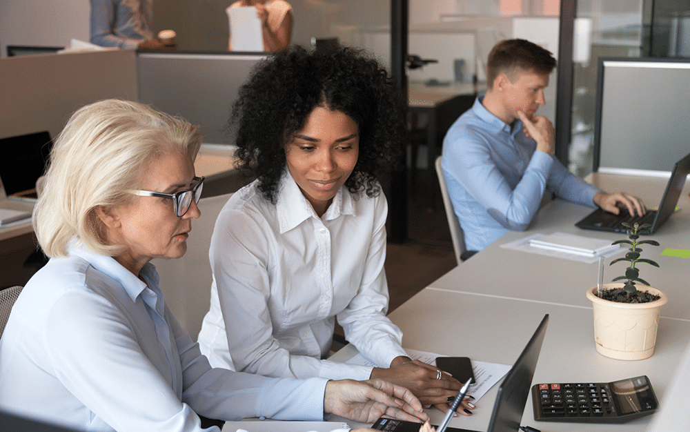 women going over something while man is alone looking at his computer